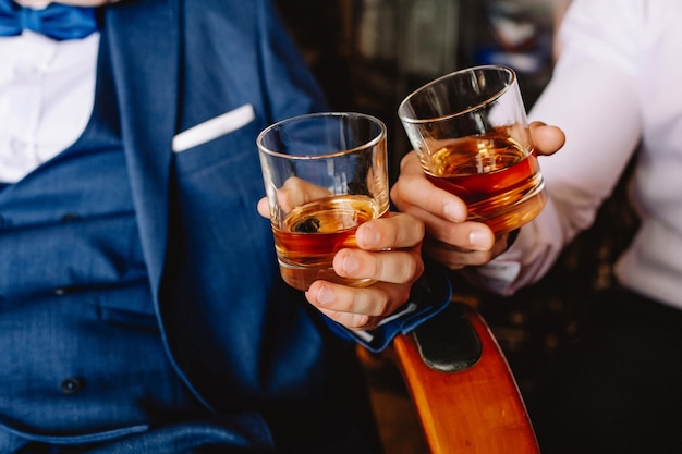 Two men holding a glass of whiskey in the groom39s room Cheers