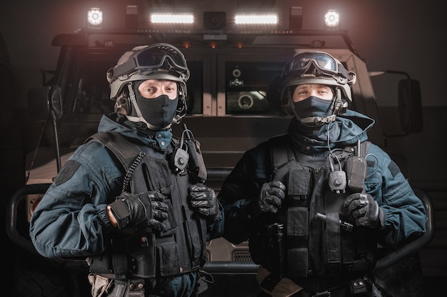 Two men in military uniforms stand in a hangar with a truck