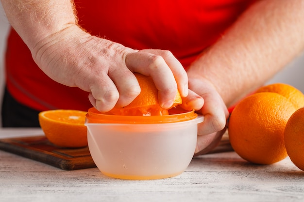 Two men's hands squeezing the juice from a orange