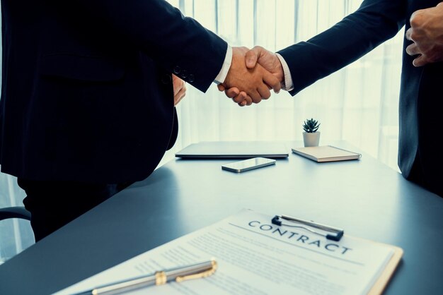 Two men shaking hands over a contract.