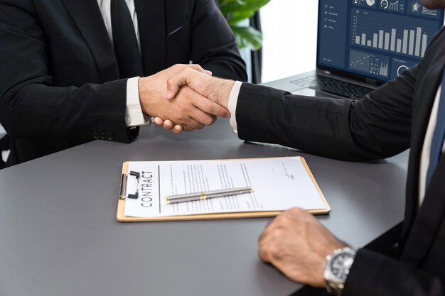 Two men shaking hands over a document with a graph on it