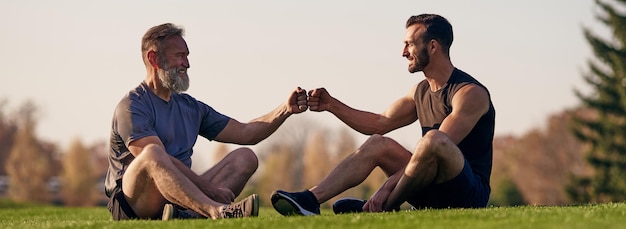 草の上に座って挨拶する二人の男