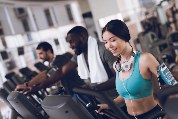 Two men and smile woman practicing on the treadmills