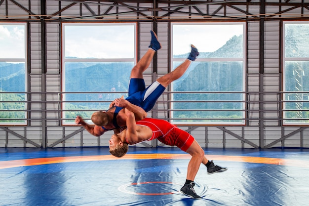 Two men in sports wrestling tights and wrestling during a traditional Greco-Roman wrestling in fight on a wrestling mat