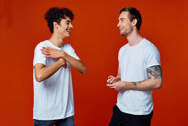 Two men stand side by side fun friendship team red background