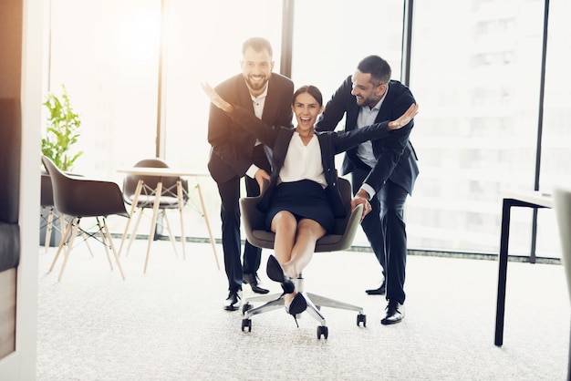 Two men in strict business suits roll their office employee.