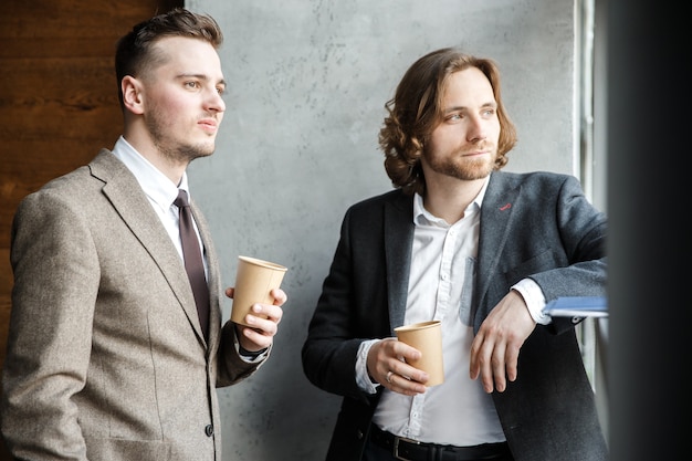 Two men in a suits are looking at the window