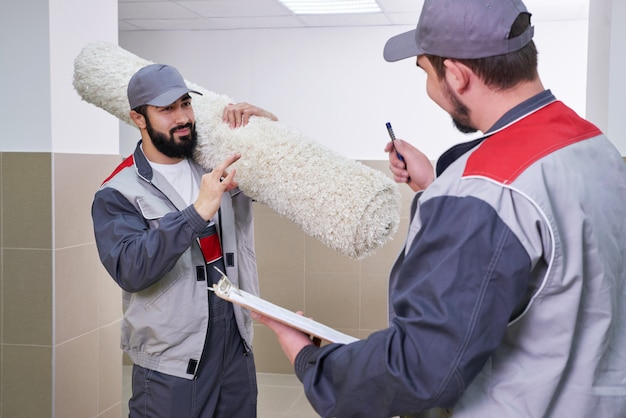 Two men taking away big carpet for cleaning service