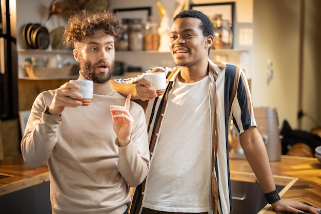 Due uomini che parlano e bevono caffè in cucina a casa