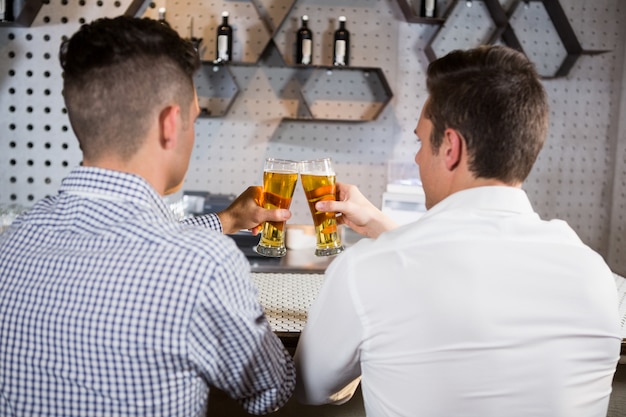 Due uomini che tostano un bicchiere di birra