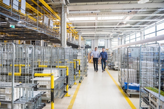 Foto due uomini che camminano nell'officina della fabbrica