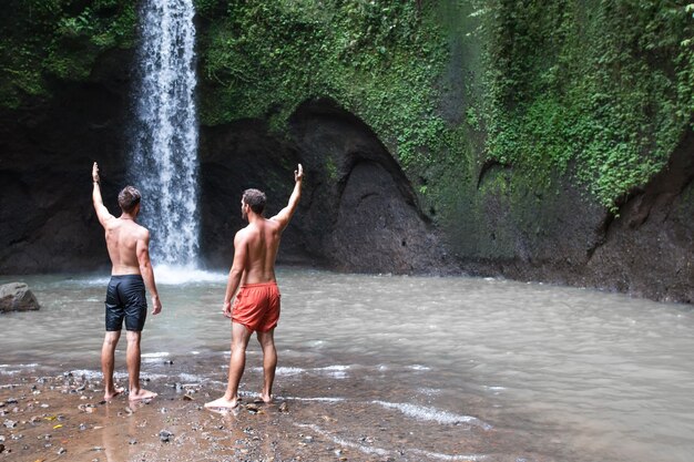 Due uomini con le mani in alto vicino alla bellissima cascata di tibumana a bali