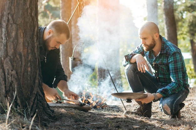 Two men with a knife cutting fish in forest