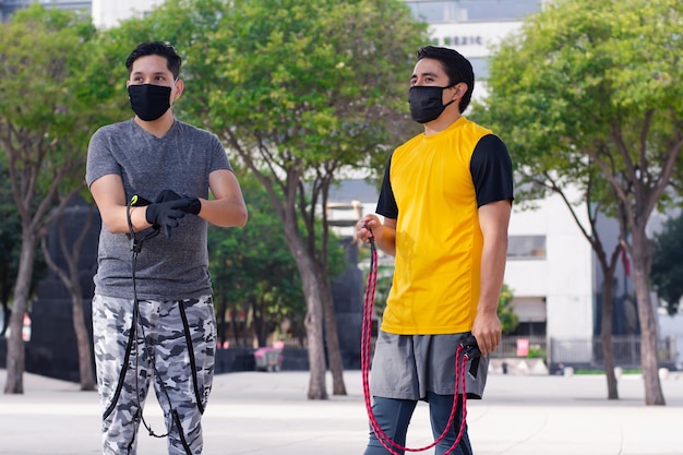 Two men with masks talking and holding jumping ropes together