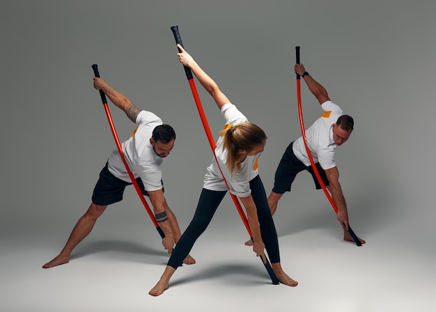 Photo two men and woman aikido fighters with wooden fight stick posing in studio fight demonstration
