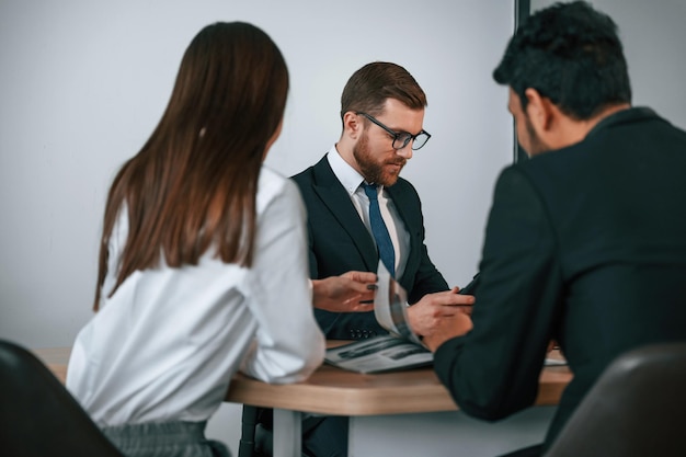 two men and woman are sitting in the office and working