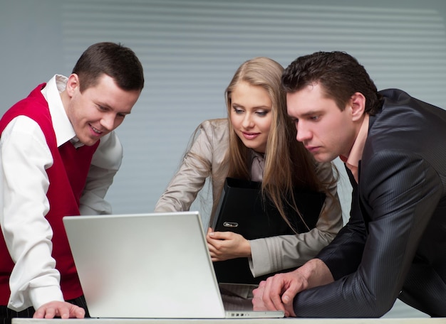 Two men and woman working with a computer in the office