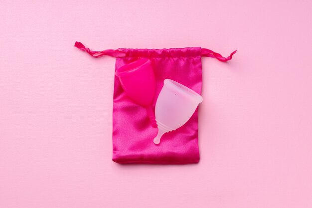 Photo two menstrual cups on pink background top view copy space