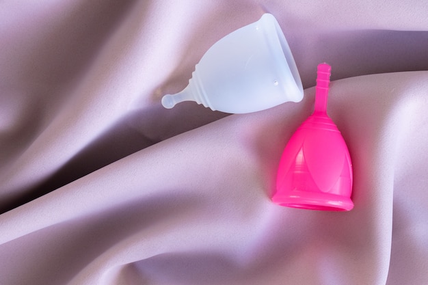 Two menstrual cups on silk pink fabric