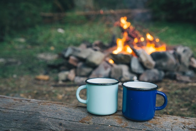 Two metal cups with tea fire on background