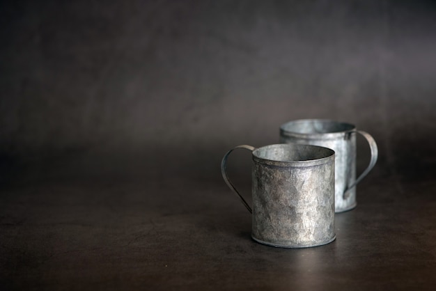 暗い灰色の背景に2つの金属の古いカップ