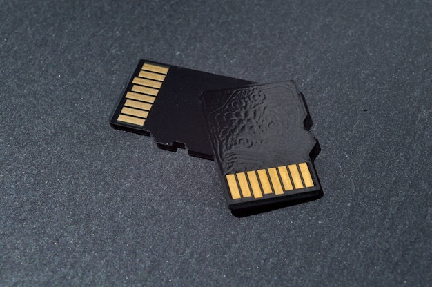 2枚のmicrosdカードが暗いテクスチャの背景に重なり、上部に金色の接点があります。閉じる。