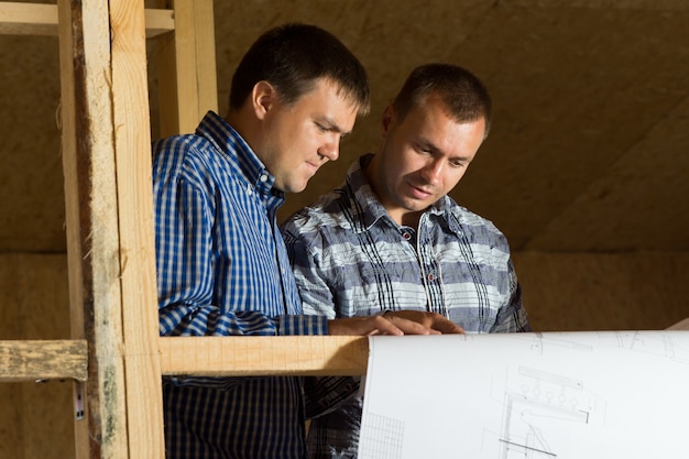 Two Middle Age Building Architects Reviewing Building Blueprint at the Site Seriously.