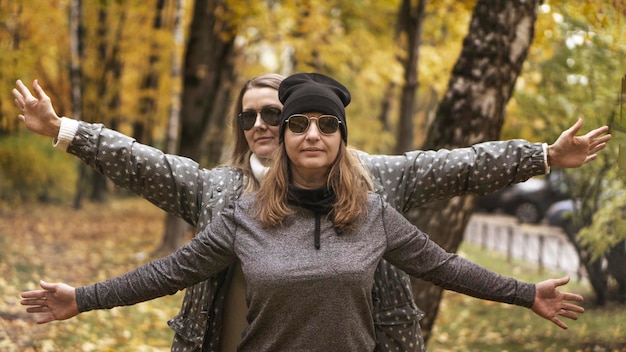 Foto due donne di mezza età, amiche, camminano nel parco autunnale e ridono. tonalità marrone d'atmosfera, effetto cinema. messa a fuoco selettiva. il concetto di relazione tra donne