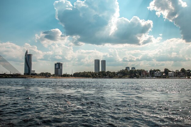 Two military speed boats patrolling the river with a historic city skyline and fluffy white clouds in the background