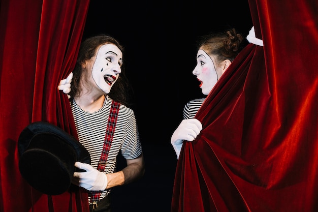 Two mime artist performing behind red curtain