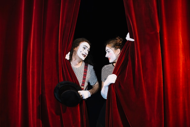 Photo two mime artist behind red curtain looking at each other