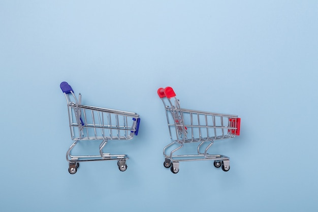 Two mini shopping carts on blue background Top view Copy space - Image