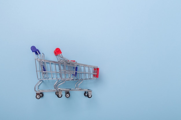 Photo two mini shopping carts on blue background top view copy space - image