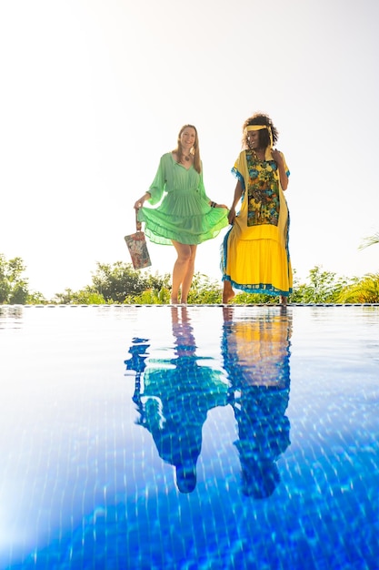 Two models with colorful dress posing in an outdoor pool