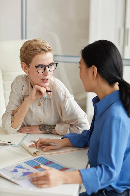 Two modern businesswomen discussing work project during meeting, copy space