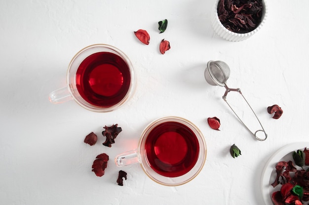 Two modern glass cups of hibiscus or hibiscus tea on a white background with dried flowers organic tea rich in vitamins and amino acids