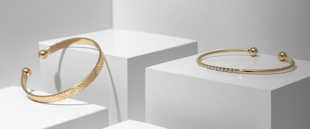 Two modern Golden bracelets on white geometric cubes