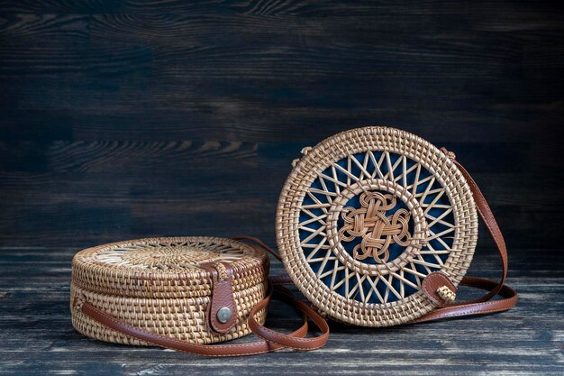 Two modern stylish round straw bag on the wooden background close up