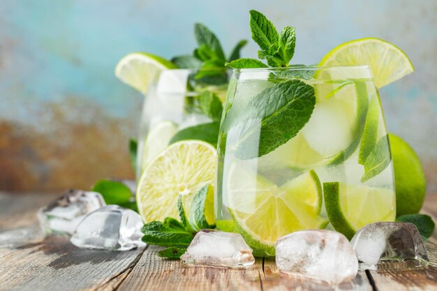 Two Mojito cocktail with ice cubes in a glass on a rustic table selective focus