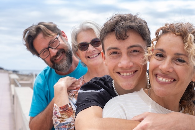 Two mothers and two son of different ages, multi-generation family. Smiling hugging and looking at camera