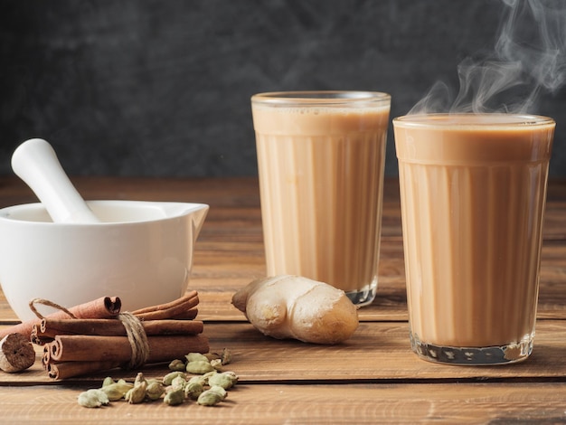 Two mugs of masala tea are on a gray table Steam comes from them