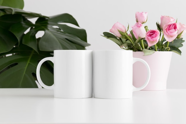two mugs mockup with pink roses in a pot and a monstera plant