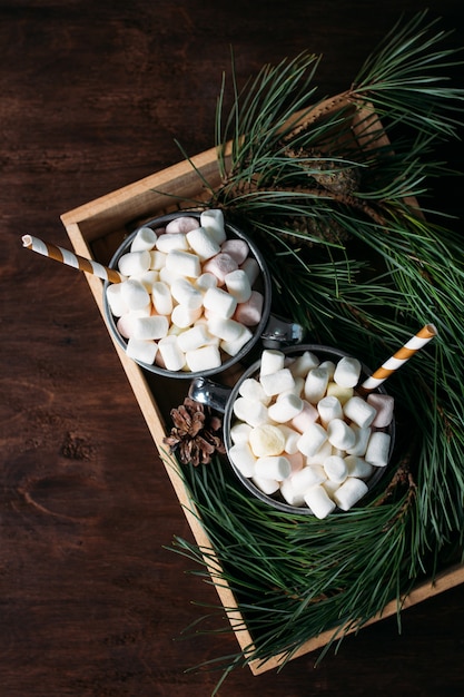 Two mugs with cocoa and marshmallows on a brown background