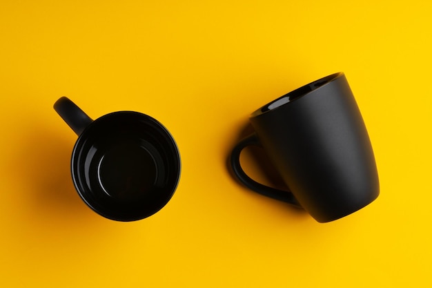 Two mugs on yellow studio background close up