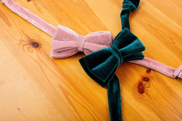 Two multicolored bow tie on a wooden background. background for\
sale. place for text. top view. pink and emerald bow tie.