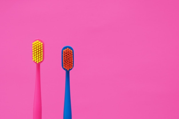 Two multicolored toothbrushes on a pink background copy spacexA