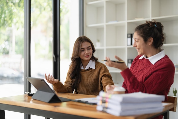 Two multiethnic professionals colleagues working together with laptop and papers in office Female mentor and young professional sitting in creative office