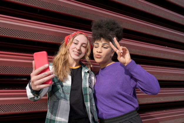 Foto due ragazze multirazziali che prendono selfie, due donne in città, donna afro e donna cauasiana