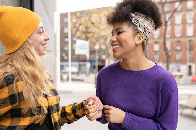 Photo two multiracial multi ethnic girlfriends hand in hand around the city