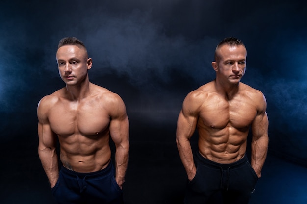 Two muscular man isolated on the black background strong male naked torso abs